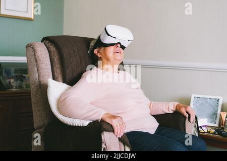 Ältere Frau mit Virtual-Reality-Brille zu Hause. Emotionale Dame mit virtuellem Headset oder 3D Brillen, die Videospiele spielen. Technologie, Augmented Real Stockfoto