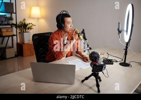 Ernsthafter Blogger, der Podcast zu emotionalen Themen in seinem Heimstudio aufnahm und seine Meinung mit Abonnenten teilte Stockfoto