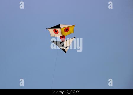 Großer Drachen, der gegen einen klaren, blauen Sommermorgenhimmel geflogen wird Stockfoto