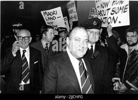 Der neuseeländische Premierminister Robert Muldoon wird am Donnerstag, den 9. Juni 1977, von dem neuseeländischen Hochkommissar Douglas Carter (links) begleitet und passiert Demonstranten vor dem Neuseeland-Haus in London. Muldoon besuchte London, um an der Commonwealth Leaders Conference teilzunehmen. Kredit: Rob Taggart/Alamy Stockfoto
