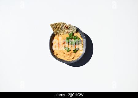 Kichererbsen-Hummus-Dip mit Pita-Brot auf einer blauen Keramikschale, oben auf weißem Hintergrund mit Platz für Text Stockfoto