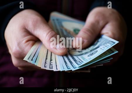 Weißer Mann zeigt Dollarscheine in seiner Hand in Nahaufnahme Vorderansicht Stockfoto