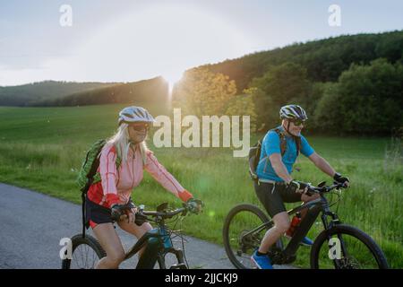 Aktives Seniorenpaar, das auf dem Trail im Sommerpark Elektrofahrräder fährt, gesundes Lifestyle-Konzept. Stockfoto