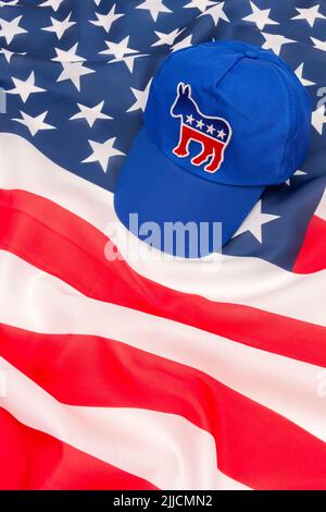 Blaue DNC-Kappe mit dem Esel-Emblem und US Stars and Stripes Flagge. Für die Präsidentschaftswahlen 2024 in den USA und die Vernichtung der Demokraten durch die republikanische Rote Welle. Stockfoto