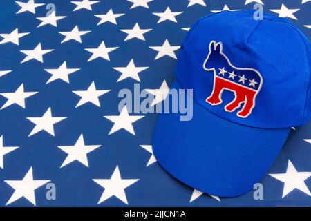 Blaue DNC-Kappe mit dem Esel-Emblem und US Stars and Stripes Flagge. Für die Präsidentschaftswahlen 2024 in den USA und die Vernichtung der Demokraten durch die republikanische Rote Welle. Stockfoto