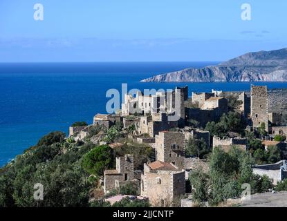 Die steinernen Türme und zerstörten Häuser von Vathia mit der dramatischen Küste des Deep Mani im Hintergrund, südpeloponnes, Griechenland. Stockfoto