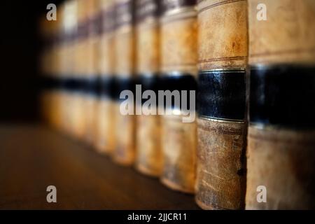 Alte Ledergesetzbücher oder Gesetzbücher auf dem Regal gestapelt Stockfoto