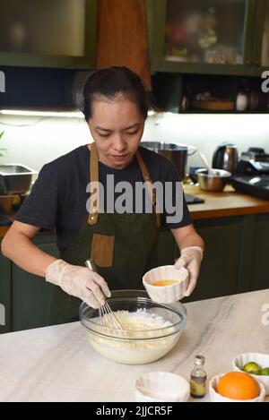 Junge Vietnamesin, die Teig für einen Kuchen mischt Stockfoto