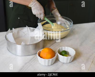 Hände in Gummihandschuhen, die Eigelb in einer Schüssel rühren Stockfoto