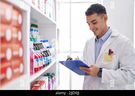 Junger hispanischer Apotheker, der auf einem Dokument in der Apotheke schreibt Stockfoto