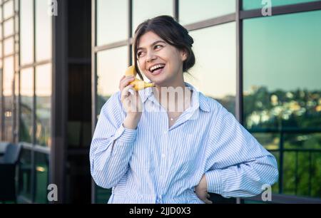 Lustige junge Frau hält eine Banane wie ein Telefon. Stockfoto