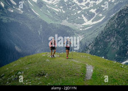 Arkhyz, Russland - 2. Juli 2022: Zwei männliche Sportler gehen auf dem Bergpfad des Arkhyz X Run Stockfoto