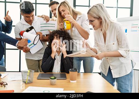 Gruppe von Geschäftsmitarbeitern, die zu einem gestressten Partner im Büro schreiend sind. Stockfoto