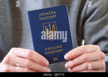 Ukrainischer biometrischer Pass in der Hand seines Besitzers in Nahaufnahme. Stockfoto