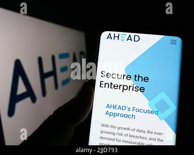 Person mit Mobiltelefon und Website des US-amerikanischen IT-Unternehmens AHEAD Inc. Auf dem Bildschirm mit Logo. Konzentrieren Sie sich auf die Mitte des Telefondisplays. Stockfoto