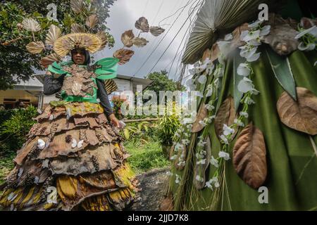 Bogor, Indonesien. 24.. Juli 2022. Eine Frau im Naturkleid aus Blättern, Blumen und Wurzeln nimmt am 24. Juli 2022 an einer Naturmodeparade 'Zurück zur Kulturerhaltung der Natur' in Bogor, West Java, Indonesien Teil. (Foto von Andi M Ridwan/INA Photo Agency/Sipa USA) Quelle: SIPA USA/Alamy Live News Stockfoto