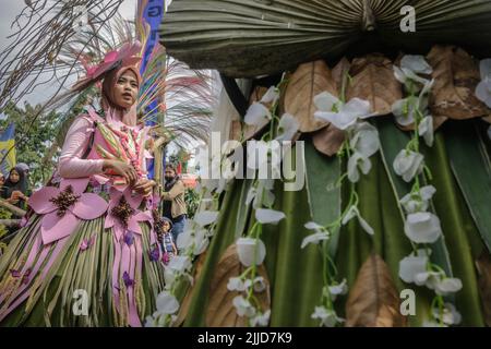 Bogor, Indonesien. 24.. Juli 2022. Eine Frau im Naturkleid aus Blättern, Blumen und Wurzeln nimmt am 24. Juli 2022 an einer Naturmodeparade 'Zurück zur Kulturerhaltung der Natur' in Bogor, West Java, Indonesien Teil. (Foto von Andi M Ridwan/INA Photo Agency/Sipa USA) Quelle: SIPA USA/Alamy Live News Stockfoto