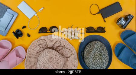 Mann und Frau kombinieren Urlaubszubehör auf dem hellgelben Hintergrund. Platz für Text oder Logo. Draufsicht. Konzept: Familienreise. Stockfoto