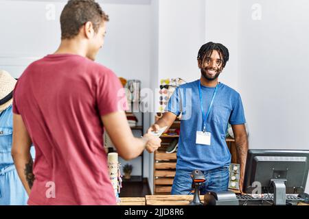 Zwei Männer, Ladenbesitzer und Kunde, die im Bekleidungsgeschäft mit Dollars einkaufen Stockfoto