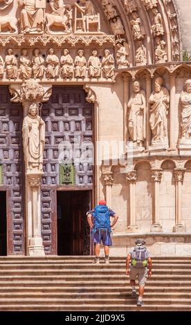 Zwei Pilger, die den Camino de Santiago auf den Stufen zur Kathedrale der Heiligen Jungfrau Maria in der spanischen Stadt Burgos, Spanien, besuchen Stockfoto