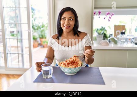 Hispanische Brünette Frau essen Spaghetti in der Küche Stockfoto