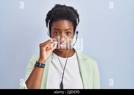 afroamerikanische Frau trägt Call Center Agent Headset Mund und Lippen geschlossen als Reißverschluss mit den Fingern. Geheim und leise, Tabu reden Stockfoto