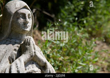 Alte Steinfigur der betenden Heiligen Maria auf dem Friedhof Stockfoto