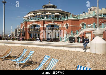 Neu renovierte Shelter Hall an der Promenade am Brighton Beach in East Sussex, England. Mit Menschen, die sitzen und vorbeigehen. Stockfoto