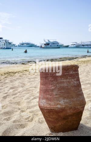 Lehmurne am Strand, vor dem Hintergrund des Meeres mit schneeweißen Yachten an hellen sonnigen Tag. Vertikales Foto. Nahaufnahme. Selektiver Fokus. Stockfoto