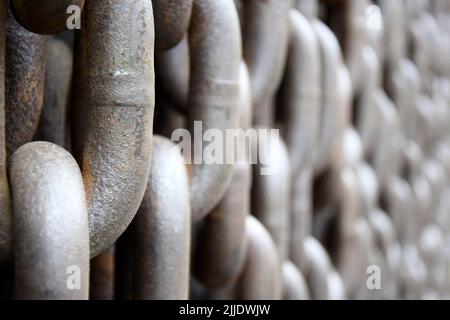 Rostig alt braun Eisenketten, Hintergrund. Wand von hängenden vertikal massiven Ketten. Nahaufnahme. Selektiver Fokus. Stockfoto