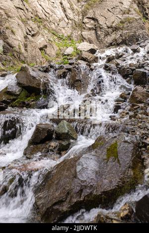 Der Gebirgsfluss fließt schnell aus der Nähe über Felsen. Stockfoto