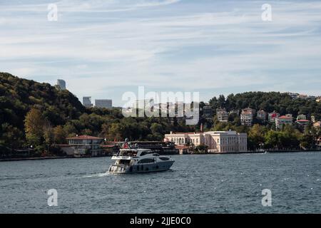 Blick auf eine Yacht, die auf dem Bosporus und dem Baltalimani-Viertel auf der europäischen Seite Istanbuls vorbeifährt. Es ist ein sonniger Sommertag. Wunderschöne Reiseszene. Stockfoto