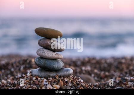 Kieselsteinpyramide am Strand bei Sonnenuntergang. Konzept von zen, Stabilität, Harmonie, Balance und Meditation, Raum kopieren. Stockfoto