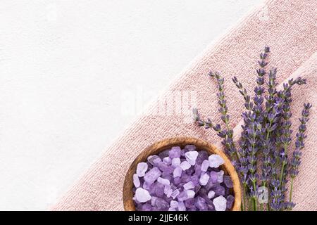 Lavendelblüten, Badesalz in Holzschüssel und rosa Handtücher auf hellem Hintergrund. SPA, Körperpflegekonzept. Draufsicht, Platz für Text kopieren Stockfoto