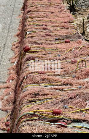 Fischernetze, die an der Hafenmauer angelegt wurden, um in der Sommersonne auszutrocknen. Keine Personen. Stockfoto