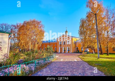 Der malerische Herbstpark des Jeletski-Himmelfahrtsklosters mit gelben Birken, Blumenbeeten und monastischen Zellen im Hintergrund, Tschernihiw, Ukraine Stockfoto