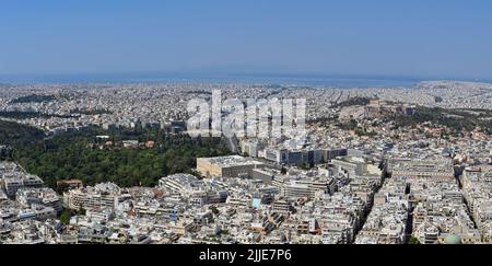 Athen, Griechenland - Mai 2022: Panoramablick auf Häuser und Gebäude in der Stadt mit Blick auf den Hafen von Piräus. Auf der rechten Seite befindet sich die Akropolis. Stockfoto