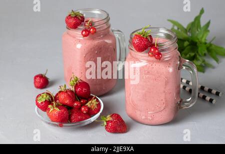 Proteincocktail aus Erdbeeren, roter Johannisbeere, Joghurt und Honig auf grauem Hintergrund Stockfoto