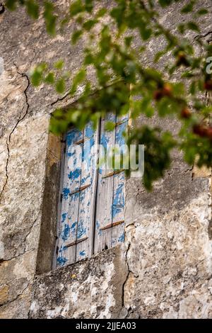 Blätternde blaue Farbe auf verzweifelten hölzernen Fensterläden auf alten typisch griechischen rustikalen oder ländlichen Landhäusern auf der Insel kreta in griechenland, schäbig chic. Stockfoto