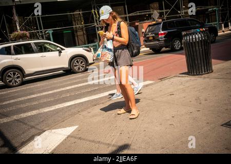 Ablenkende Frau, die sich während der Hitzewelle, die am Freitag, den 22. Juli 2022, zu sehen war, für den Sommer in Chelsea in New York kleidete. Für das kommende Wochenende, an dem die Temperaturen voraussichtlich bis Sonntag 98 Grad erreichen werden, wurde eine Wärmeempfehlung herausgegeben. (© Richard B. Levine) Stockfoto