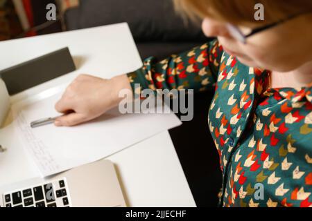 Defcous weibliche Hand schreiben mit Stift. Unkenntlich elegante Frau, die im Büro am Computer arbeitet. Beginn oder Ende eines Arbeitstages. Arbeitsbereich. Draufsicht. Ti Stockfoto