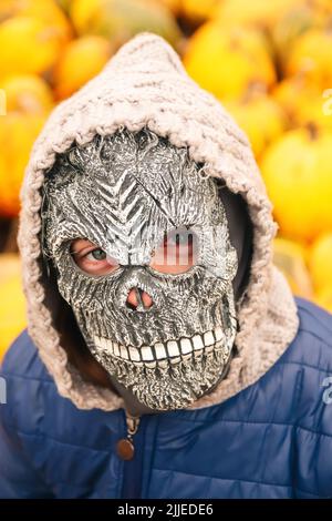 Unschärfe Halloween Menschen Porträt. Person in grimmiger Reaper Maske auf gelbem Kürbis Hintergrund stehend. Halloween-Horror. Schädelgeist. Grimmiger Schnitter. Schädel Stockfoto