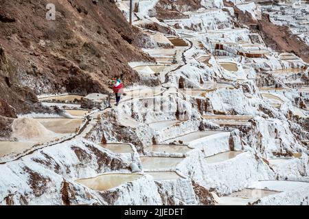 Arbeiter, die durch Salzpfannen, Salineras de Maras Salzminen, Cusco, Peru gehen Stockfoto