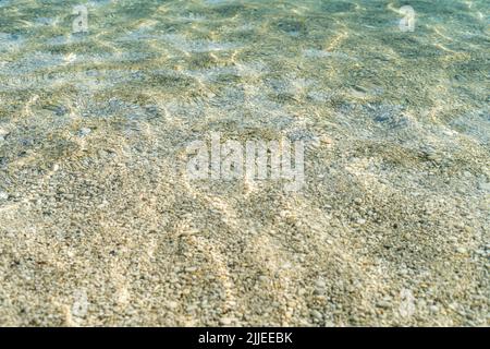 Nahaufnahme des klaren Meeres mit Kieselsteinen und Wellen. Stockfoto