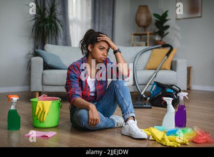 Frustriert müde unglücklich junge schwarze Frau Hausfrau leiden unter einer Menge Hausarbeit sitzen auf dem Boden Stockfoto