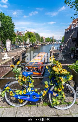 Sint Antoniesluis, auf dem Oudeschans-Kanal, Fahrrad mit Sonnenblumen geschmückt, Grachtenrundfahrt, Café, De Sluyswacht, Amsterdam, Niederlande Stockfoto