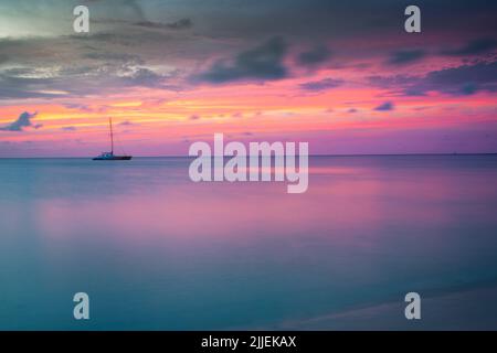 Schiffe bei einem friedlichen und dramatischen Sonnenuntergang auf dem karibischen Meer von Aruba, den Niederländischen Antillen. Stockfoto