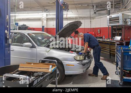 Aurora, Colorado - Russell Bacon behebt das Ölleck eines Autos durch die Hände des Carbenters. Die gemeinnützige Organisation repariert Fahrzeuge, die alleinerziehenden Müttern gehören, bei der Reduzierung Stockfoto