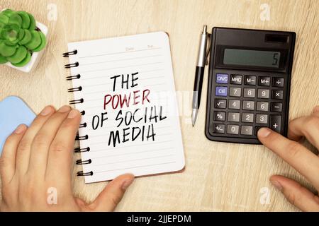 Hand mit rotem Stift. Kaffeetasse. Stick. Tastatur und weißer Hintergrund. DIE MACHT DER SOCIAL MEDIA-Zeichen in den Notizblock Stockfoto