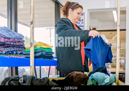 Eine Frau faltet am 23. Februar 2013 in Columbus, Mississippi, ihre Wäsche in einem Waschsalon. Der Job zahlt einen Mindestlohn. Stockfoto